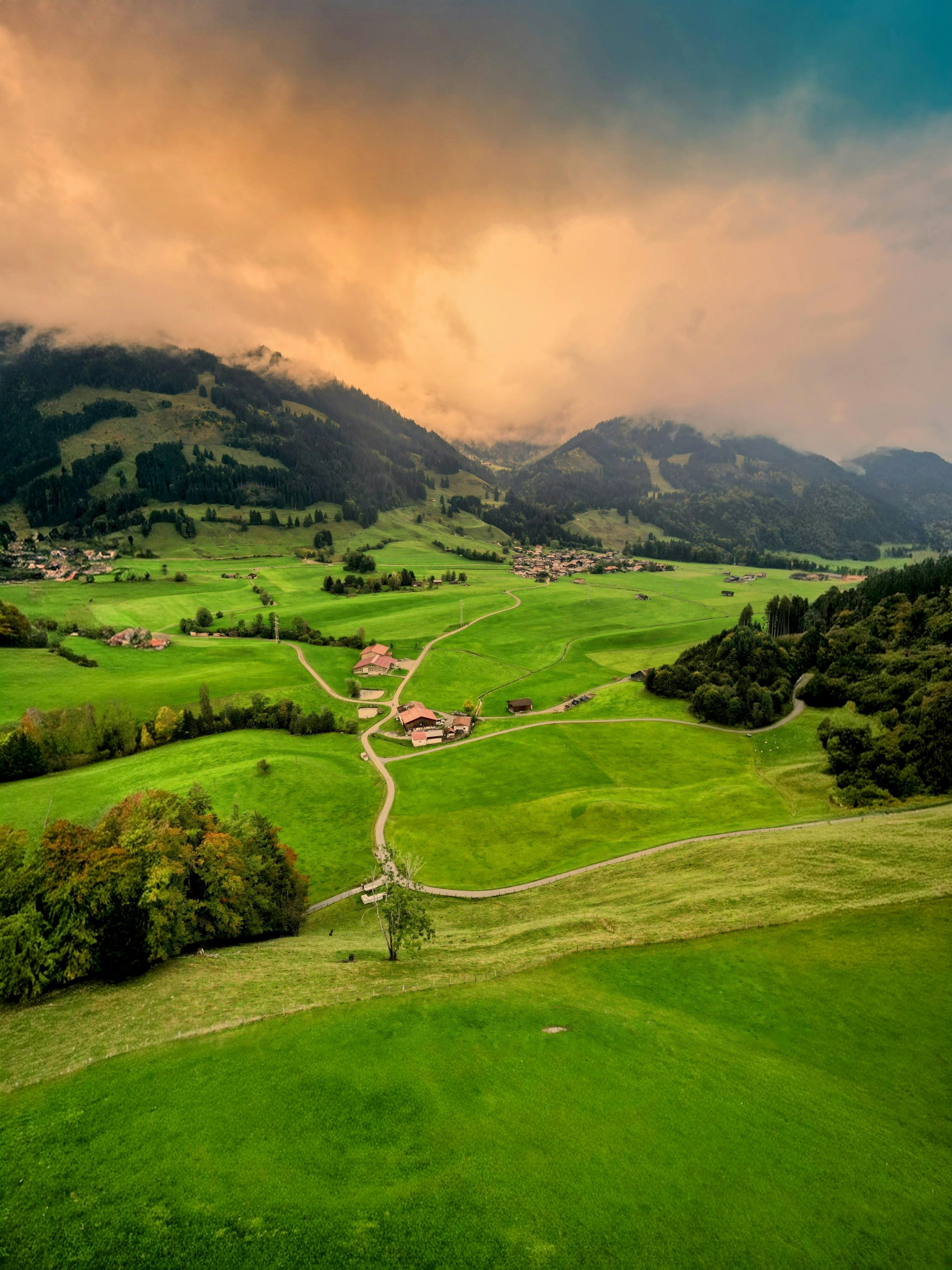 Winding road through a lush green Alpine valley at sunset
