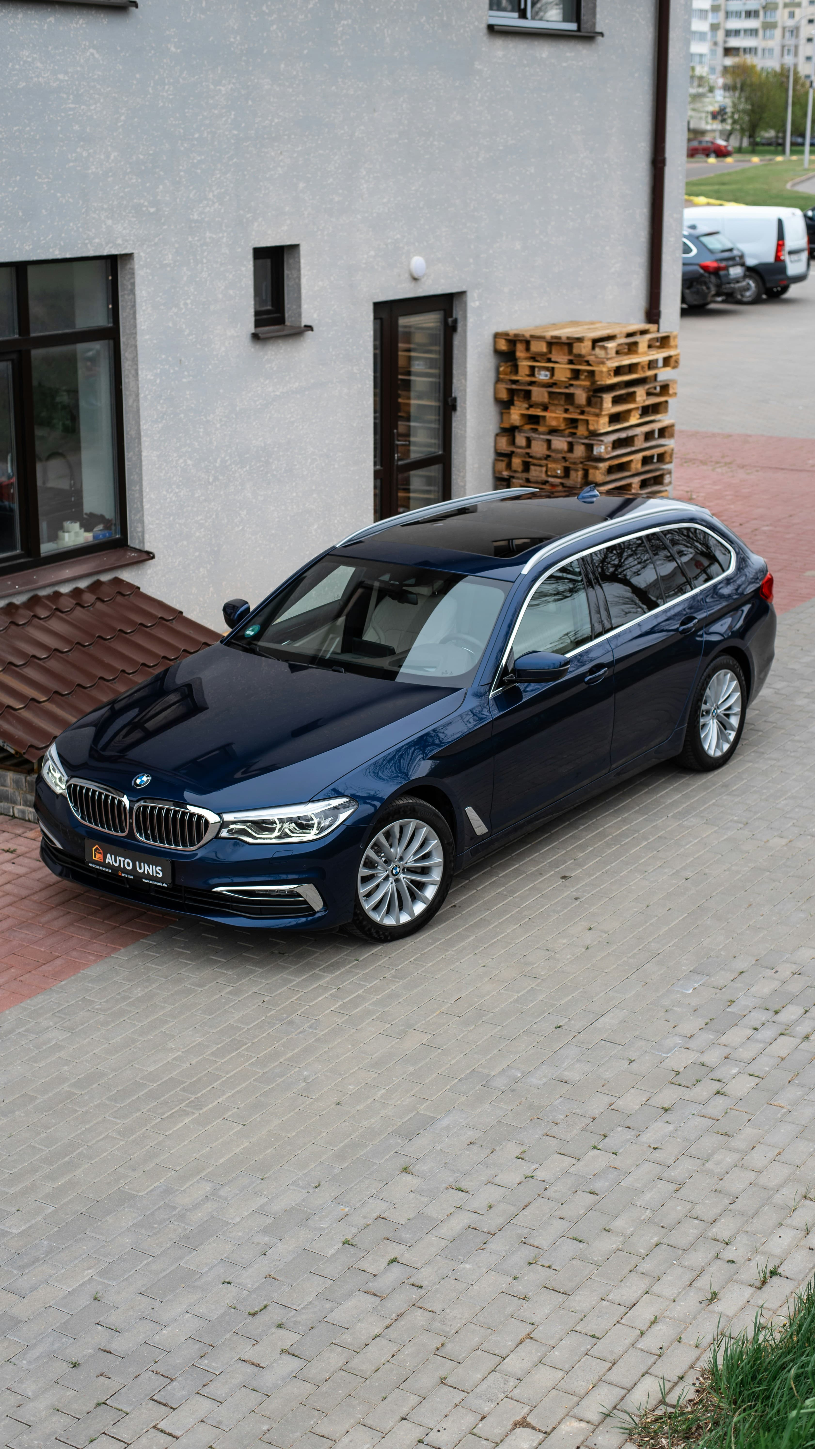 Navy blue BMW 5 Series Touring on a European cobblestone driveway