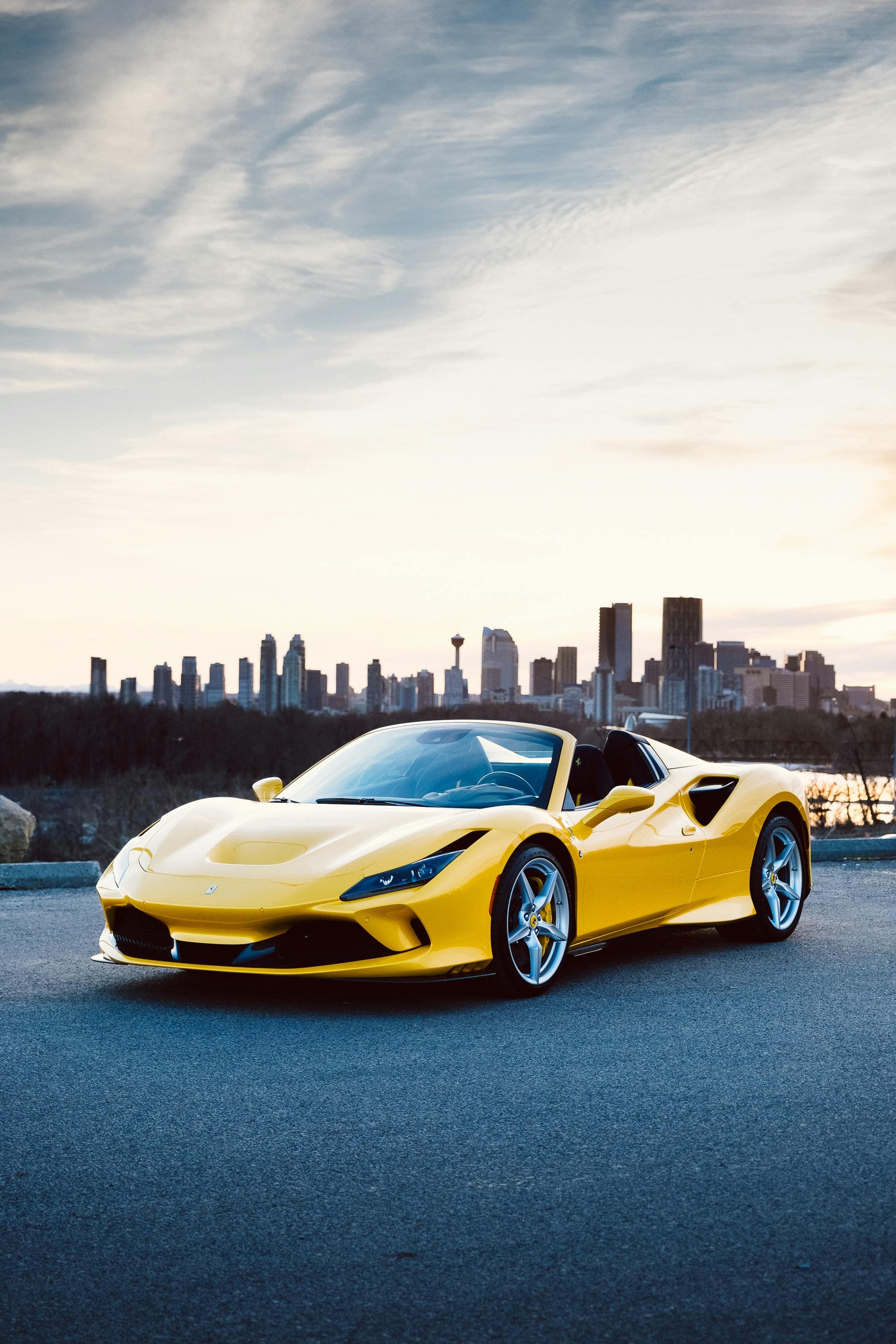 Yellow Ferrari F8 Spider convertible against a dramatic sky